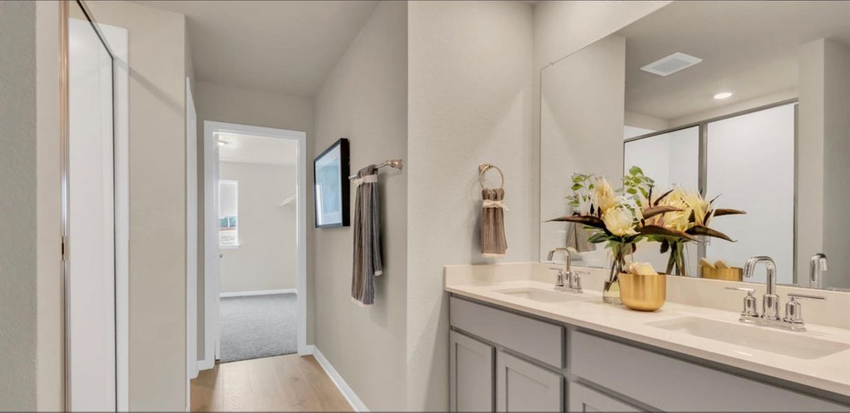 Bathroom with light wood-style floors, a shower stall, and double vanity