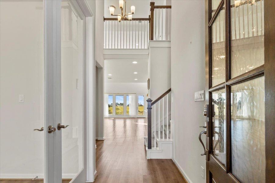 Entrance foyer with a towering ceiling, wood finished floors, a chandelier, stairway, and recessed lighting Entrance foyer with a towering ceiling, wood finished floors, a chandelier, stairway, and recessed lighting