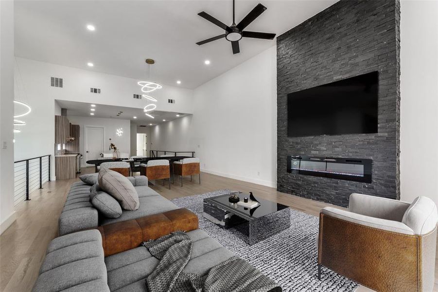 Living room with a ceiling fan, light wood-type flooring, a fireplace, recessed lighting, and high vaulted ceiling