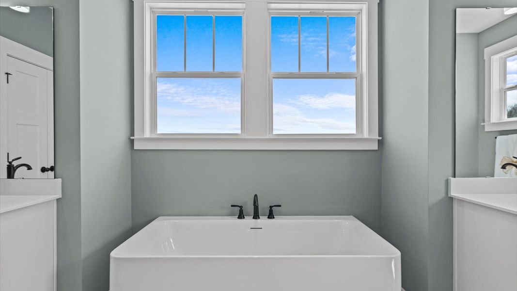 Exceptional en-suite with separate vanities, tub, and glass-enclosed tiled walk-in shower for superior everyday comfort