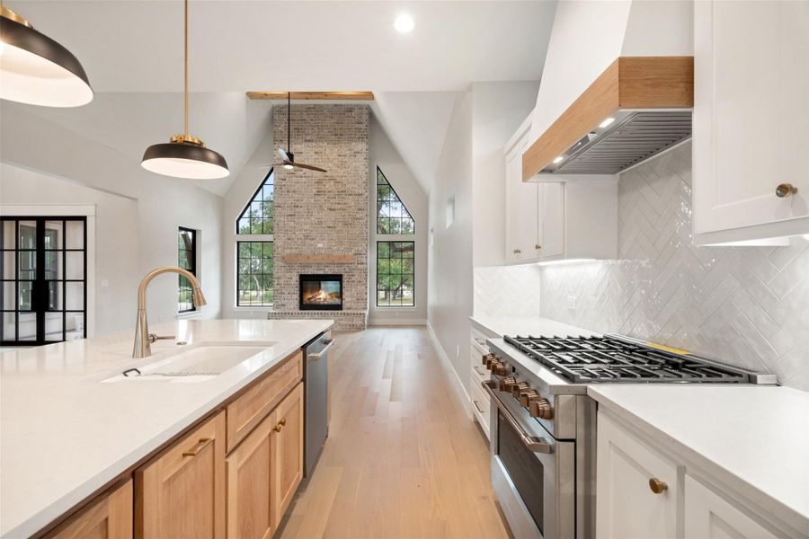 An open-concept living area boasts high ceilings, a grand brick fireplace, and an elegant kitchen island. An open-concept living area boasts high ceilings, a grand brick fireplace, and an elegant kitchen island.