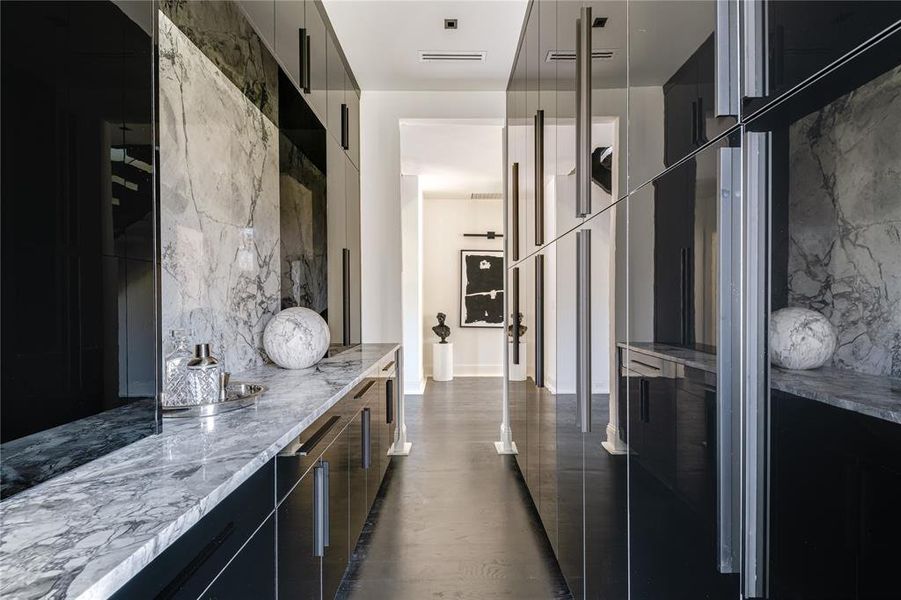 Kitchen featuring decorative backsplash, visible vents, modern cabinets, dark cabinets, and light stone counters