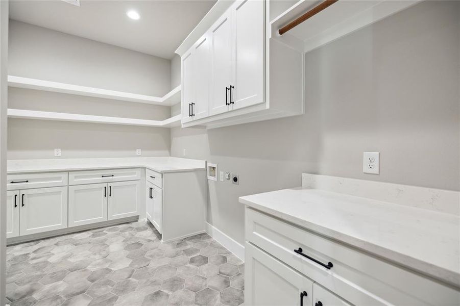 Clothes washing area with electric dryer hookup, hookup for a washing machine, and cabinets