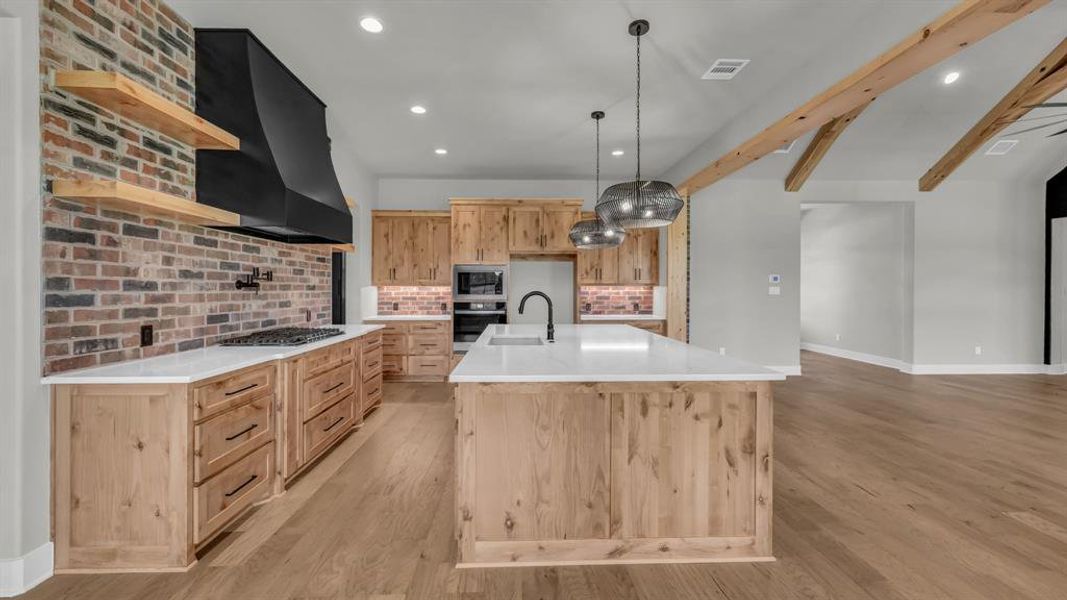 Spacious kitchen featuring an expansive island with a matte black faucet and dual pendant lighting