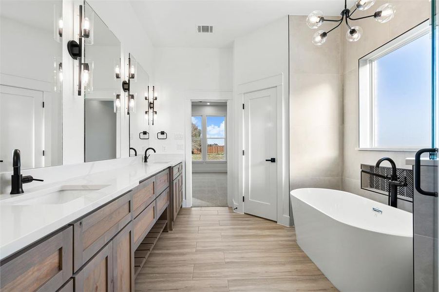 Bathroom with vanity, an inviting chandelier, and a bath