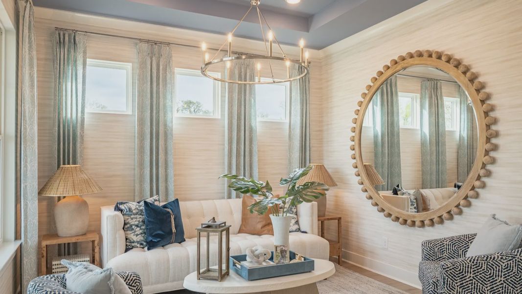 Seating area near front of home with tray ceiling and designer furnishing