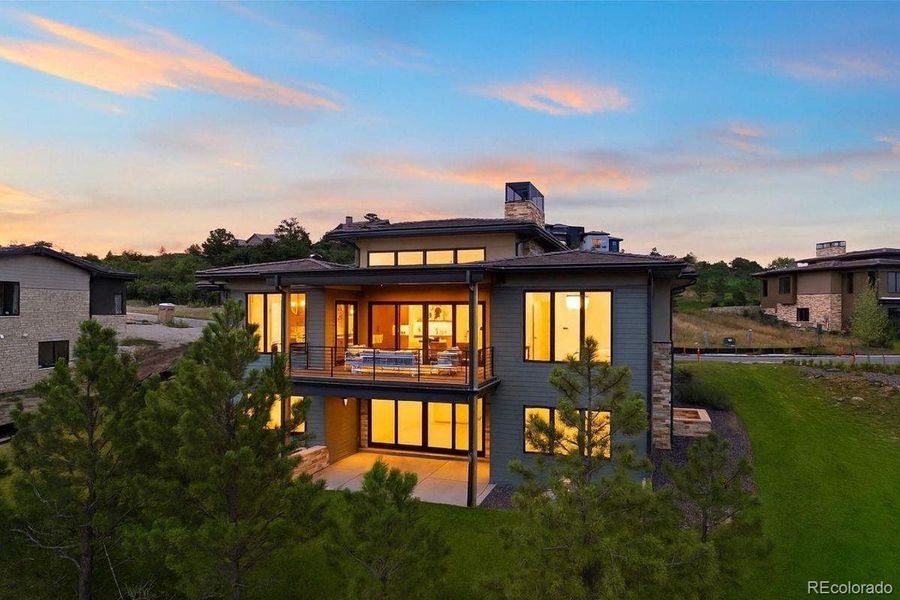 Modern two-story retreat with expansive glass walls, sleek lines, and a covered balcony overlooking serene natural surroundings.