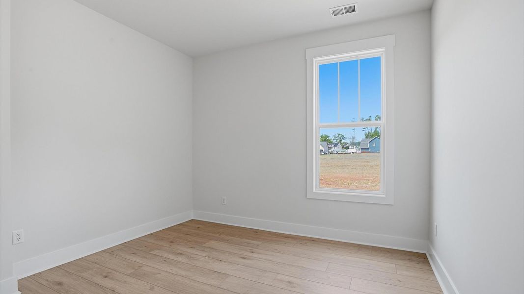 Superior hardwood flooring enhances the comfort and style of this secondary bedroom located in Greenville, SC