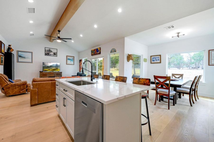 Kitchen with a breakfast bar, open floor plan, stainless steel dishwasher, light wood-type flooring, and white cabinetry