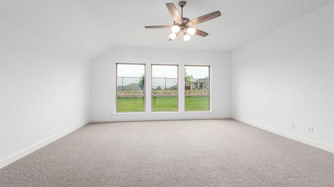 Carpeted empty room featuring ceiling fan and lofted ceiling