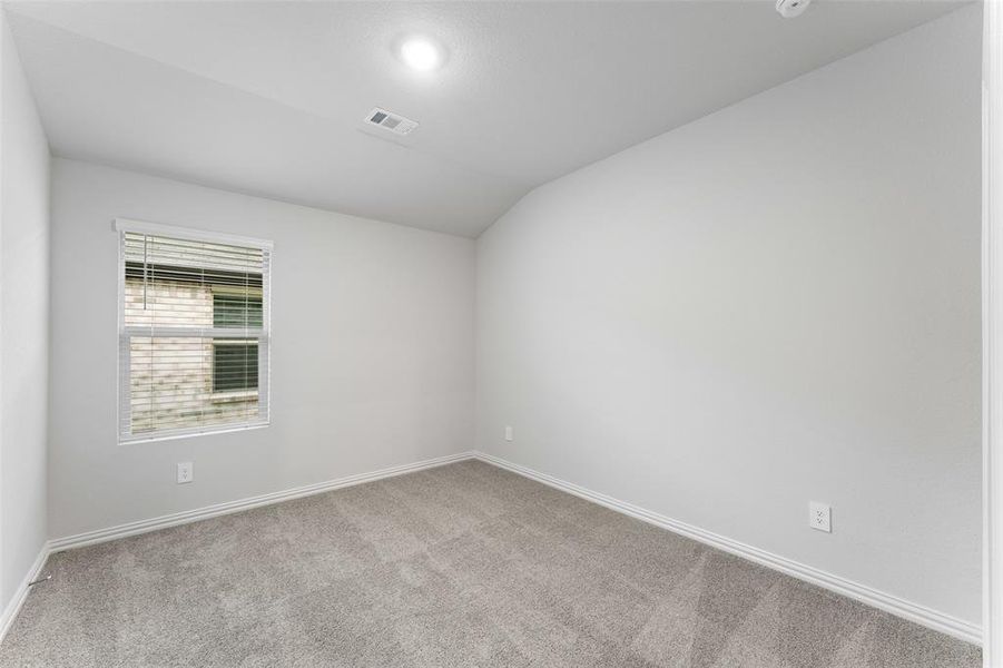 Spare room featuring lofted ceiling and carpet floors Spare room featuring lofted ceiling and carpet floors
