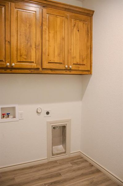 Laundry area with cabinet space, hookup for an electric dryer, washer hookup, and wood finished floors Laundry area with cabinet space, hookup for an electric dryer, washer hookup, and wood finished floors