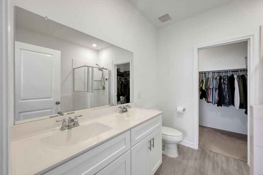 Primary bath room features dual sinks, separate shower and tub.
