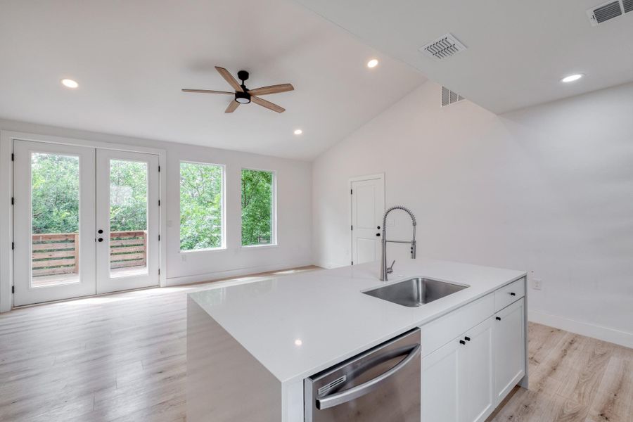 A pristine open-concept living space features vaulted ceilings, ample natural light, and a modern kitchen island with stainless steel appliances. A pristine open-concept living space features vaulted ceilings, ample natural light, and a modern kitchen island with stainless steel appliances.