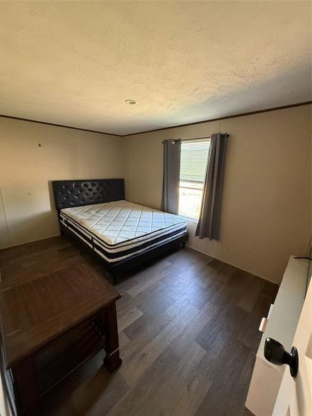 Bedroom with a textured ceiling and dark wood finished floors