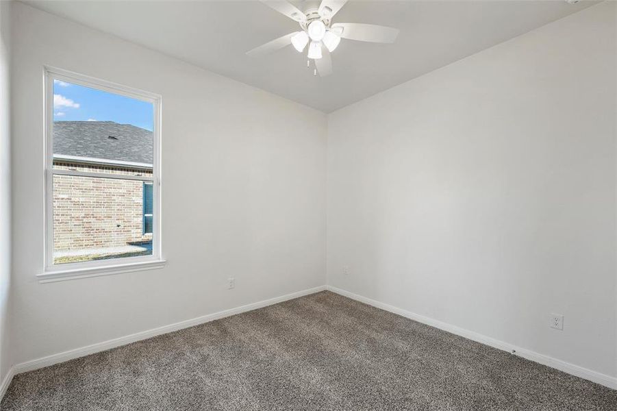 Carpeted spare room featuring baseboards and a ceiling fan