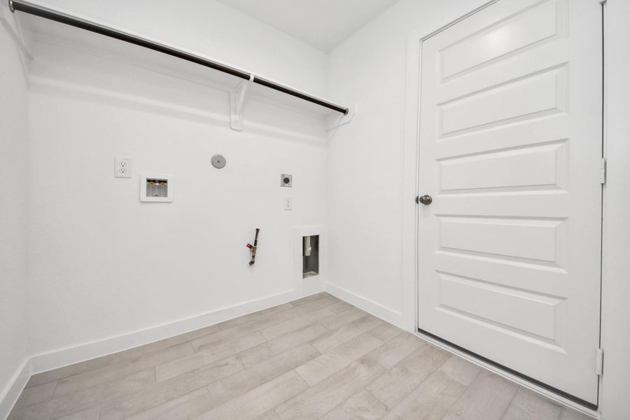 A perfect blend of functionality and comfort. Capture the essence of easy living with a first-floor laundry room, thoughtfully equipped with shelving for effortless organization. Both electric and gas connections available. Sample photo of completed home with similar floor plan. Actual colors and selections may vary.
