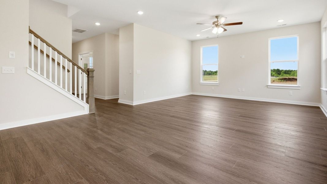 Gathering room with hard surface flooring, ceiling fan, and access to staircase Gathering room with hard surface flooring, ceiling fan, and access to staircase