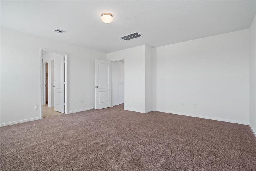 Another view of this spacious primary bedroom looking into the entry of. the primary bathroom.