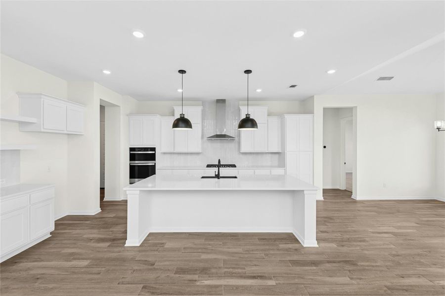 Kitchen featuring pendant lighting, white cabinetry, recessed lighting, light wood-type flooring, and a center island with sink Kitchen featuring pendant lighting, white cabinetry, recessed lighting, light wood-type flooring, and a center island with sink