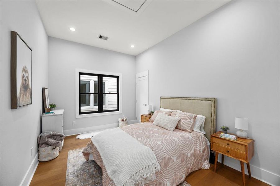 Charming bedroom featuring soft neutral tones, recessed lights, and a large window bringing in natural light.