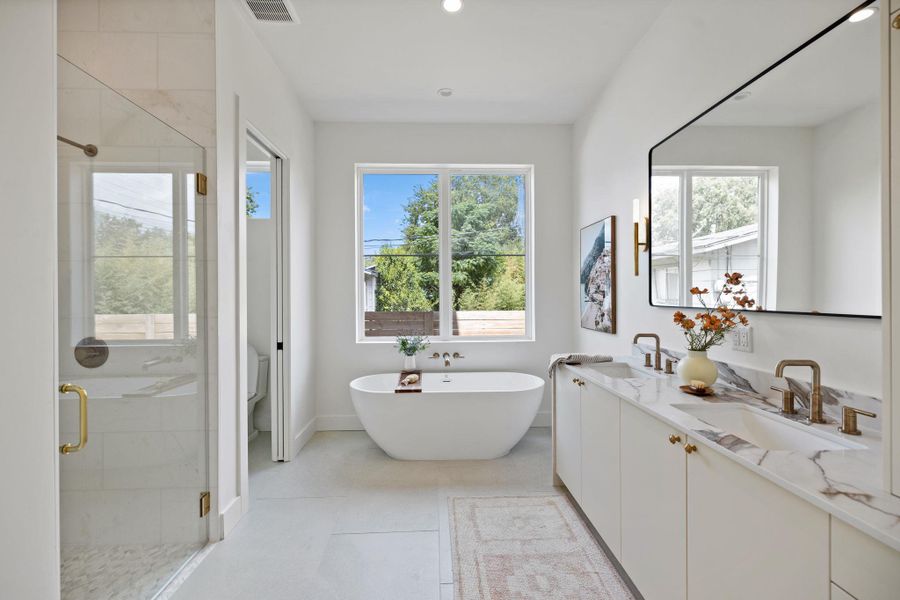 Full bath with a shower stall, a freestanding bath, double vanity, recessed lighting, and light tile patterned flooring Full bath with a shower stall, a freestanding bath, double vanity, recessed lighting, and light tile patterned flooring