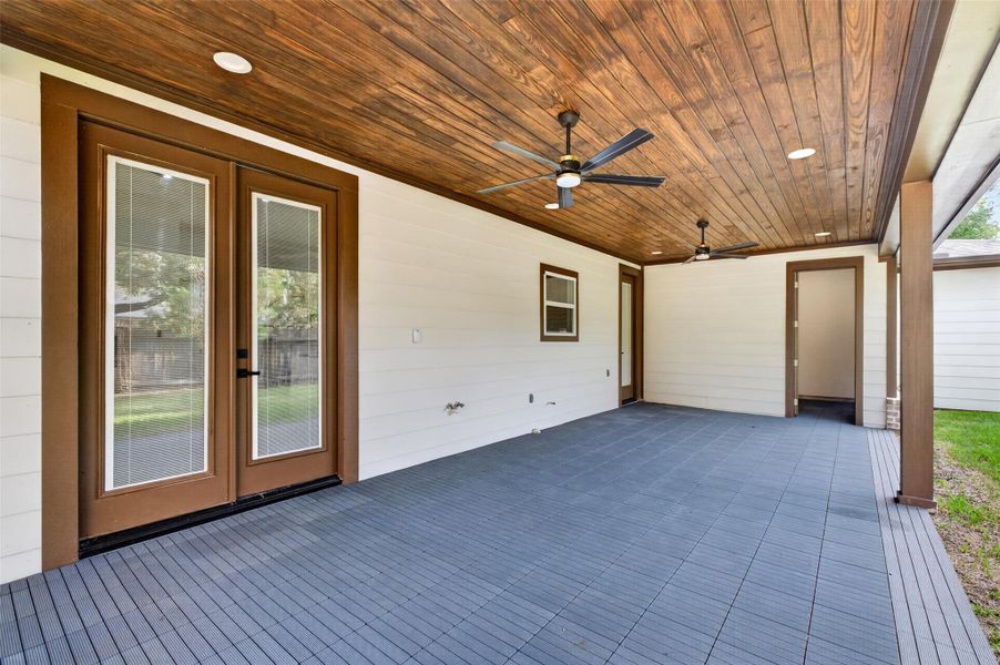 Spacious covered patio with tongue and groove elegant wood ceiling and dual ceiling fans, perfect for outdoor relaxation and entertaining.