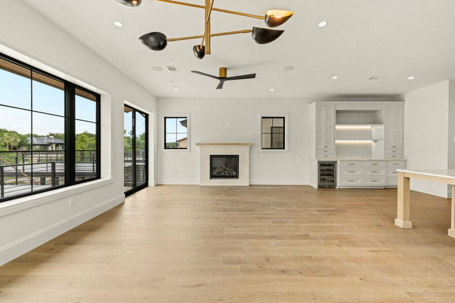 Unfurnished living room featuring wine cooler, a glass covered fireplace, baseboards, and recessed lighting