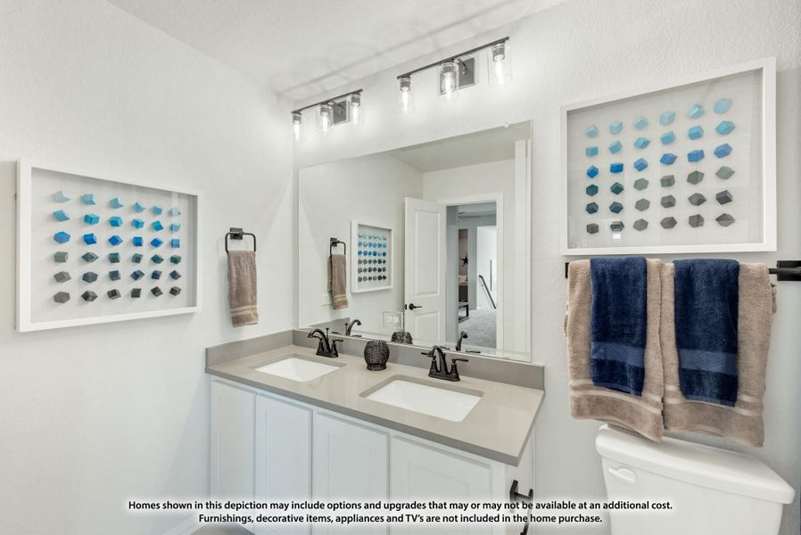 Bathroom with double sink vanity, white cabinets, gray countertop, large mirror, and wall-mounted light fixture