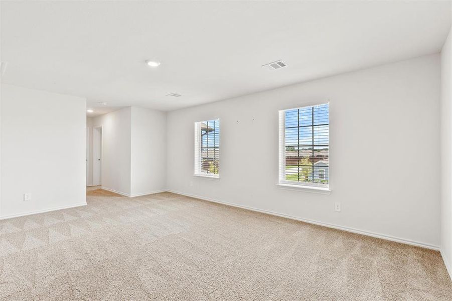 Spacious room featuring neutral carpeting, recessed lighting, and two windows with blinds