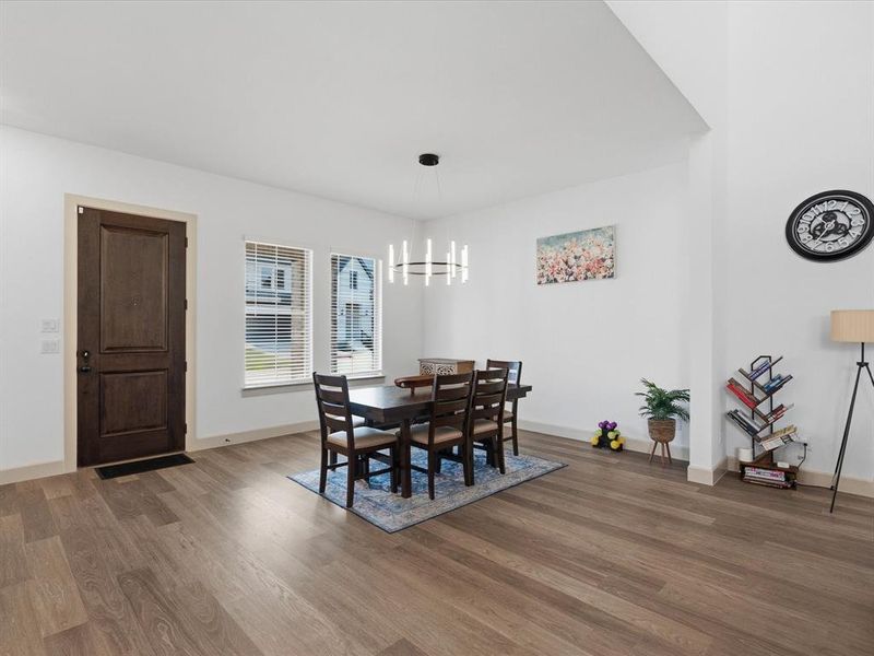 Dining area featuring wood-finish flooring, a contemporary linear chandelier, and ample natural light from two windows