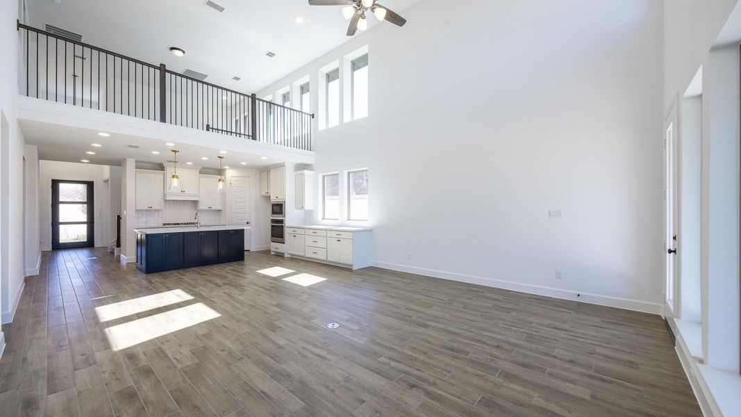 Unfurnished living room with dark wood-style floors, a high ceiling, a ceiling fan, and recessed lighting
