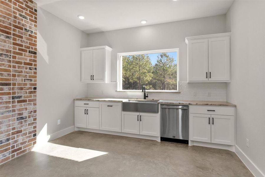 A large picture window above the kitchen sink fills the space with natural light and offers peaceful views of the backyard, creating a bright and welcoming atmosphere while you cook or clean. This thoughtful placement keeps you connected to the outdoors and enhances the open feel of the kitchen.Functionality meets convenience with a built-in pull-out trash drawer, seamlessly integrated into the cabinetry. Designed to maintain a clean, streamlined look.