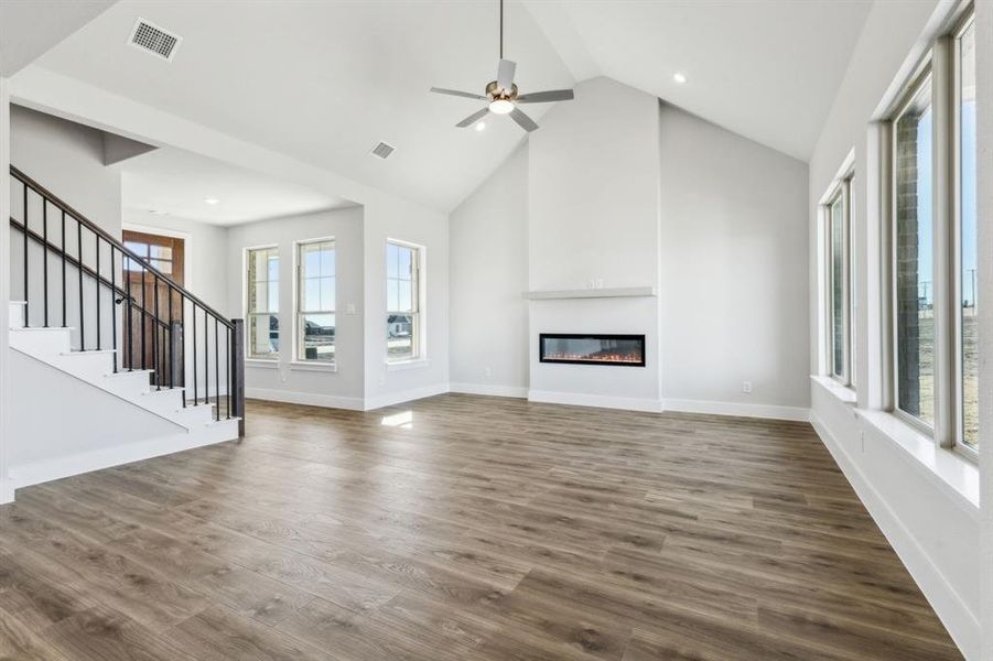 Unfurnished living room featuring ceiling fan, dark hardwood / wood-style floors, and high vaulted ceiling