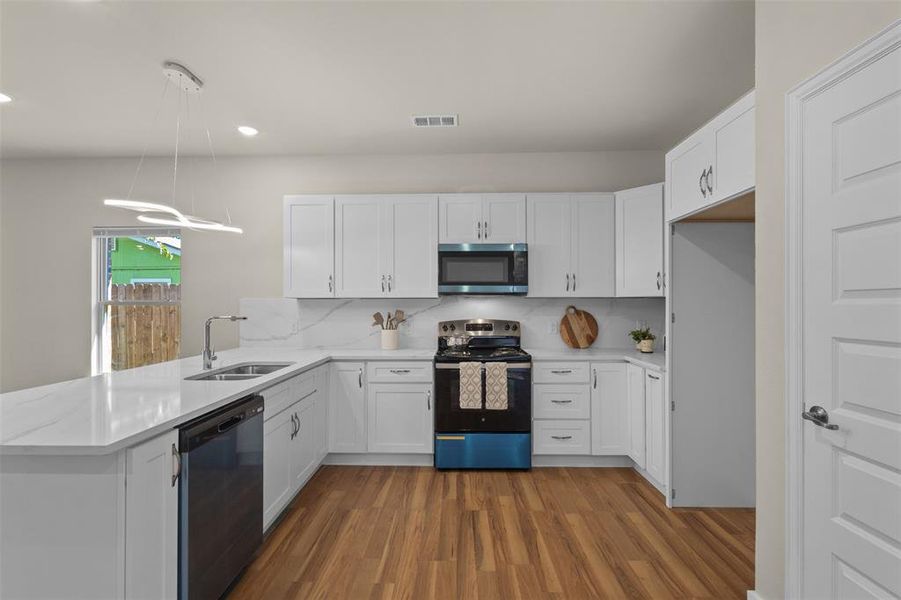 Kitchen featuring white cabinets, stainless steel appliances, backsplash, a peninsula, and dark wood-type flooring Kitchen featuring white cabinets, stainless steel appliances, backsplash, a peninsula, and dark wood-type flooring