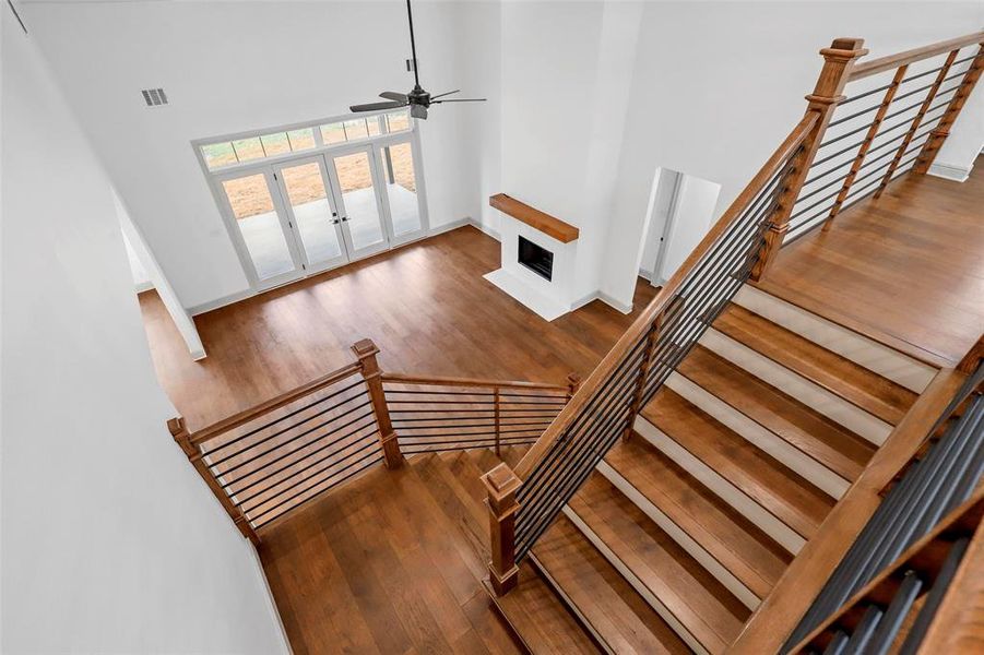 Stairway with a towering ceiling, wood-type flooring, and ceiling fan