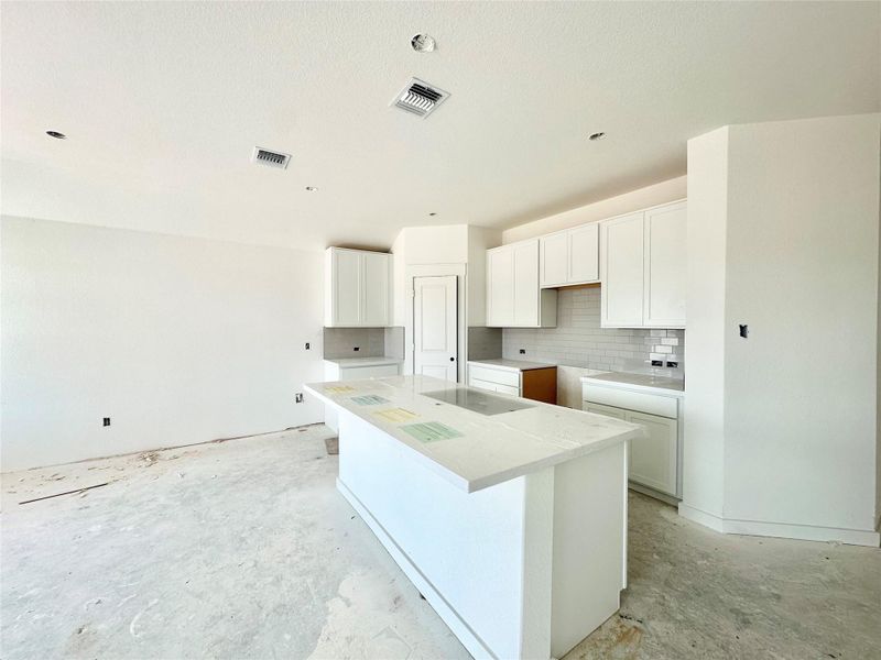 Kitchen featuring white cabinets, backsplash, a kitchen island, and concrete floors