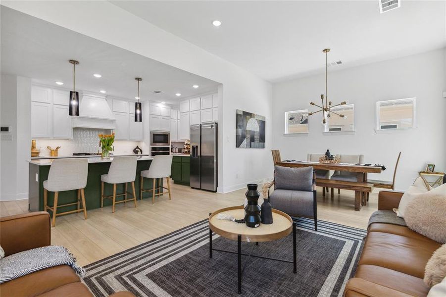 Living room with recessed lighting, visible vents, light wood finished floors, and an inviting chandelier Living room with recessed lighting, visible vents, light wood finished floors, and an inviting chandelier