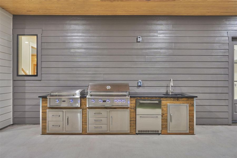 Grill night just got an upgrade. This fully equipped outdoor kitchen — complete with dual grills, sink, fridge, and storage — even has glowing blue LED-lit knobs that turn cooking after dark into its own kind of ambiance. Every detail spared, every evening elevated. Grill night just got an upgrade. This fully equipped outdoor kitchen — complete with dual grills, sink, fridge, and storage — even has glowing blue LED-lit knobs that turn cooking after dark into its own kind of ambiance. Every detail spared, every evening elevated.