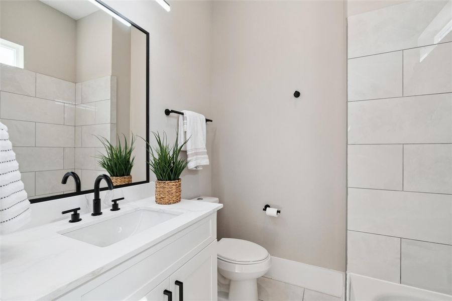 Linear geometry meets soft monochrome in this guest bath, where matte black hardware cuts through polished white surfaces.