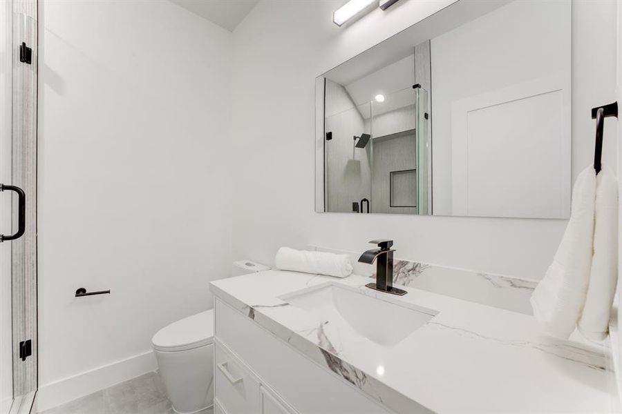 Quartz countertops, black accented hardware, and large frameless mirror.