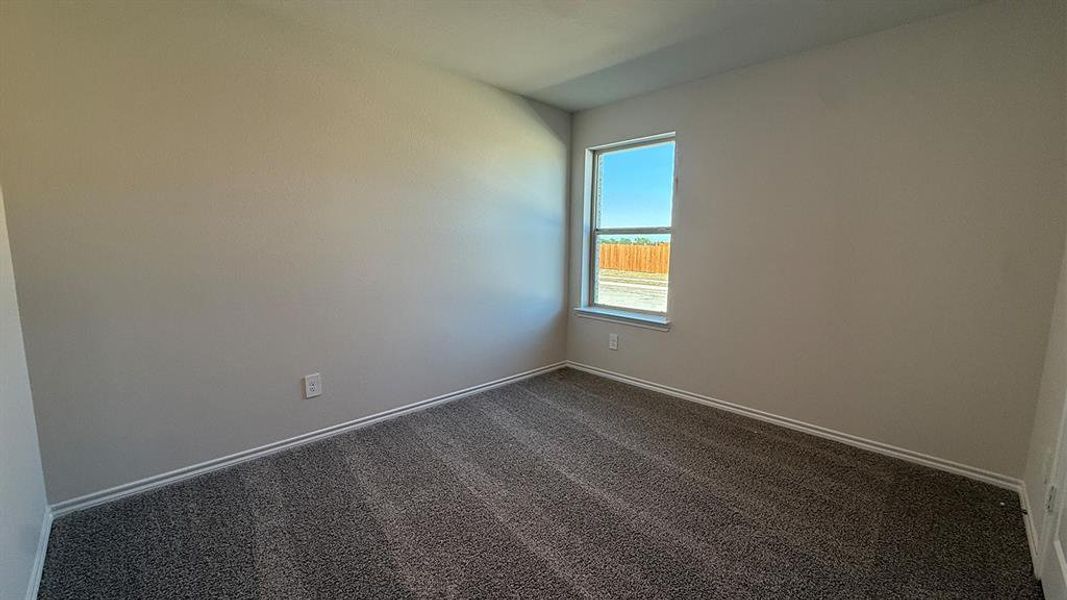 Neutral-toned room featuring a single window, light beige walls, white baseboards, and patterned gray carpet