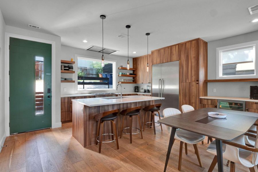 Kitchen with brown cabinets, built in refrigerator, open shelves, light countertops, and light wood finished floors