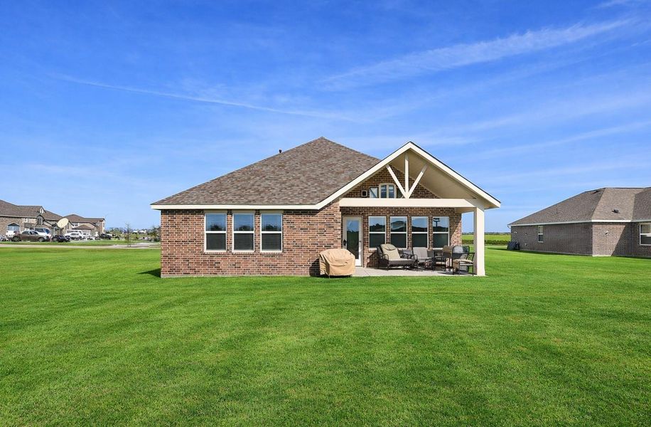 Spacious backyard. Featuring a covered patio perfect for outdoor seating and entertaining. The surrounding grassy area offers ample space for outdoor activities.