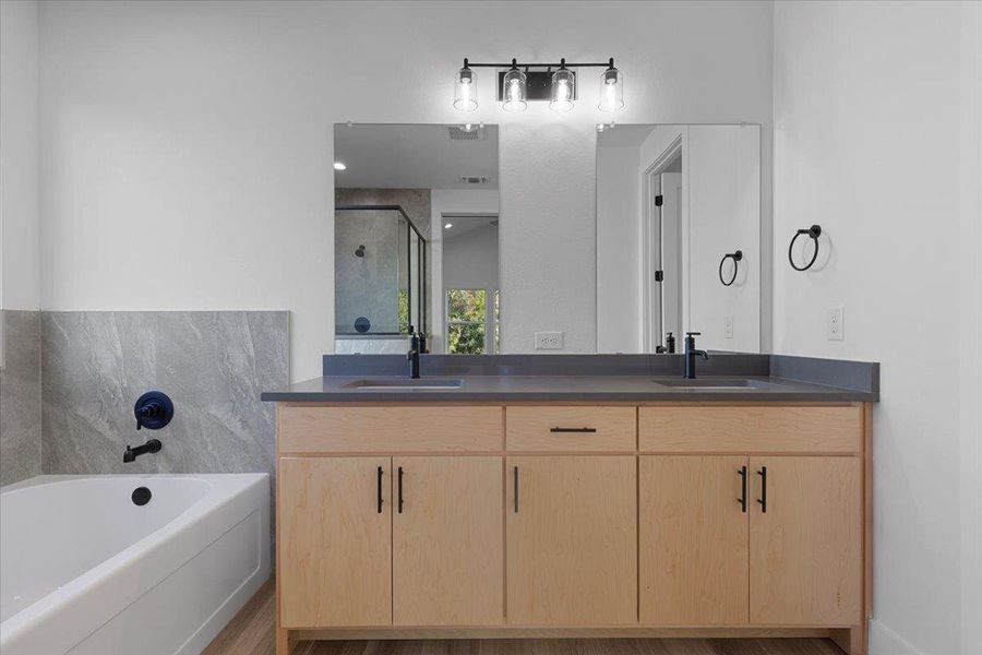 Bathroom featuring double vanity, a bath, a shower stall, and light wood-style floors Bathroom featuring double vanity, a bath, a shower stall, and light wood-style floors