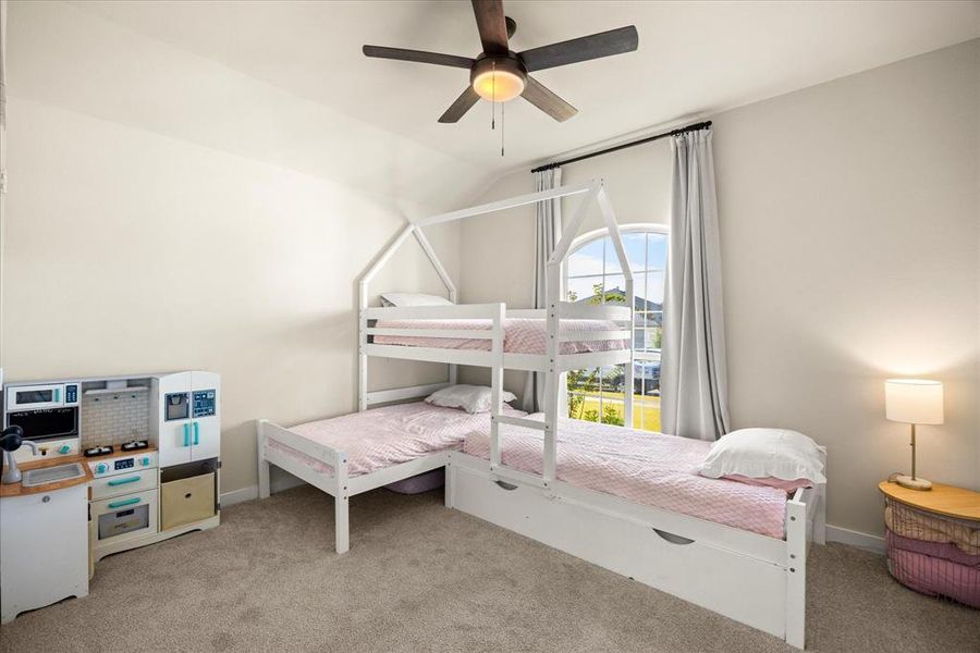 Bedroom with light carpet, ceiling fan, and vaulted ceiling