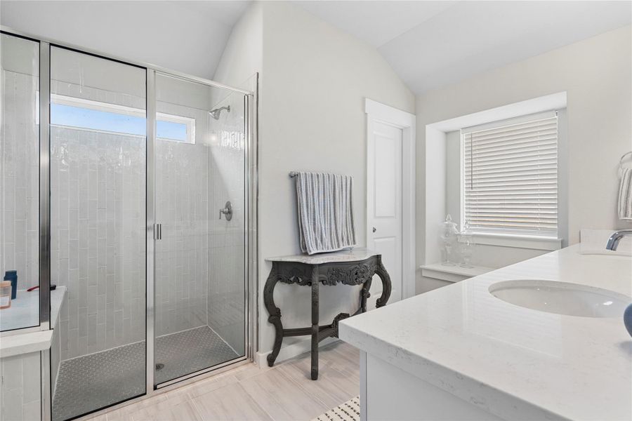 Bathroom featuring double vanity, a shower stall, and vaulted ceiling Bathroom featuring double vanity, a shower stall, and vaulted ceiling