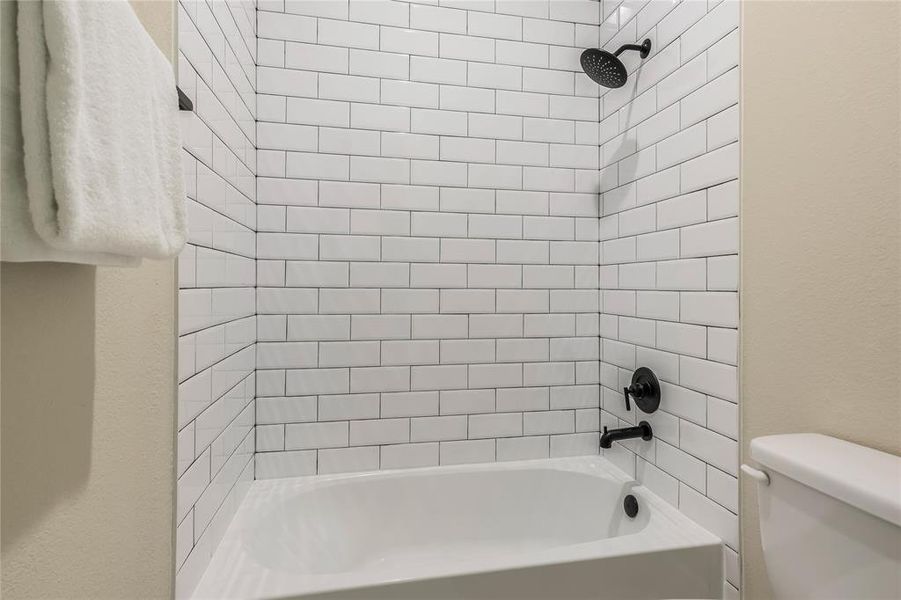 Bathroom #2 features tub and shower combination with sleek white subway tiles and matte black fixtures Bathroom #2 features tub and shower combination with sleek white subway tiles and matte black fixtures