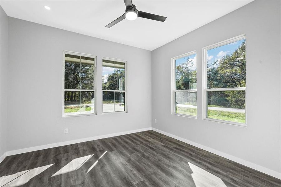 Spare room with a wealth of natural light, dark wood-type flooring, and ceiling fan