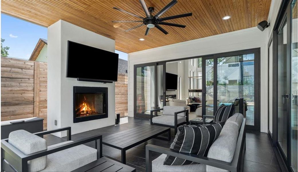 Covered patio with an outdoor living area, fireplace, and a ceiling fan